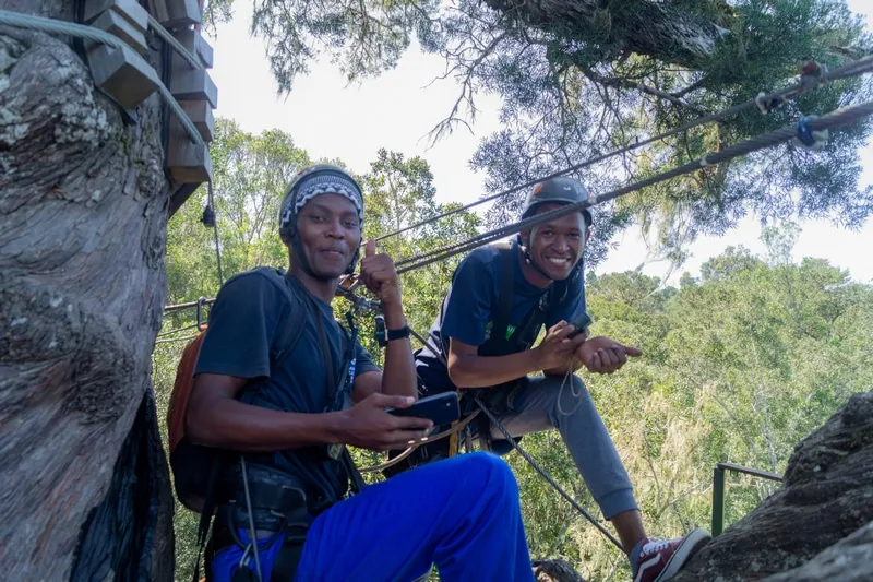 Two Canopy Tour guides in harnesses on a forest platform